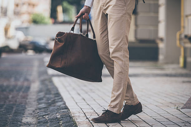 Close up of man holding leather bag while walking outdoors